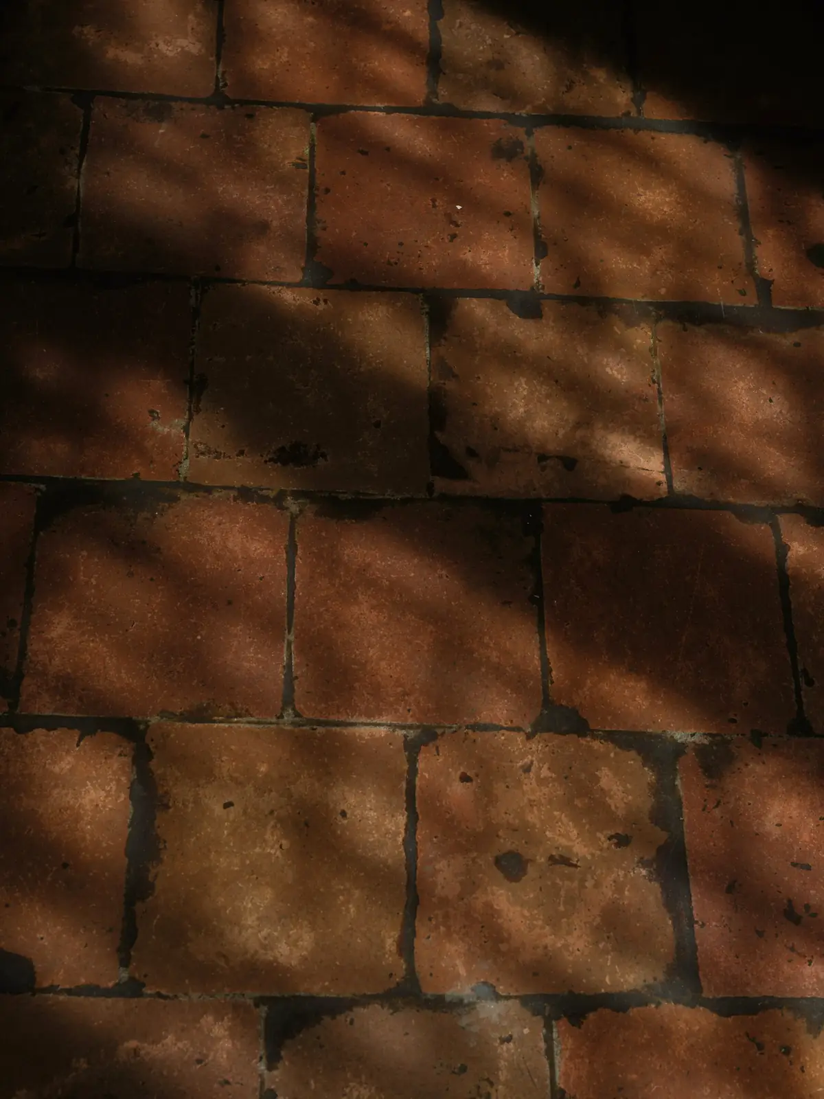 Sol en terre cuite traversé par l’ombre et la lumière d’une fin d’après-midi